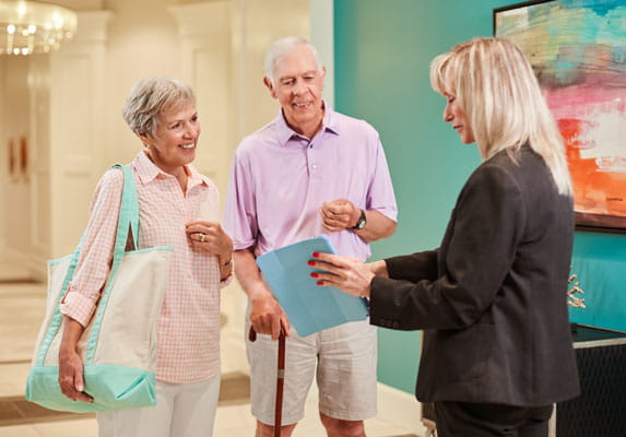 A staff member points to a tablet while meeting with two people.
