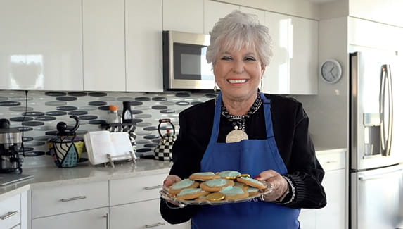 Vi at Aventura resident Susan Shovers holds a plate of cookies in her kitchen.