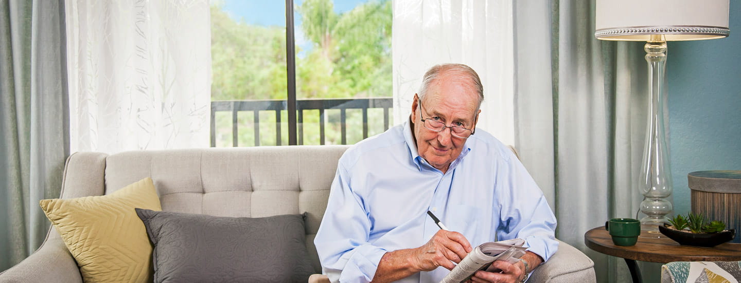 A man looks at the camera while holding a pen and paper.