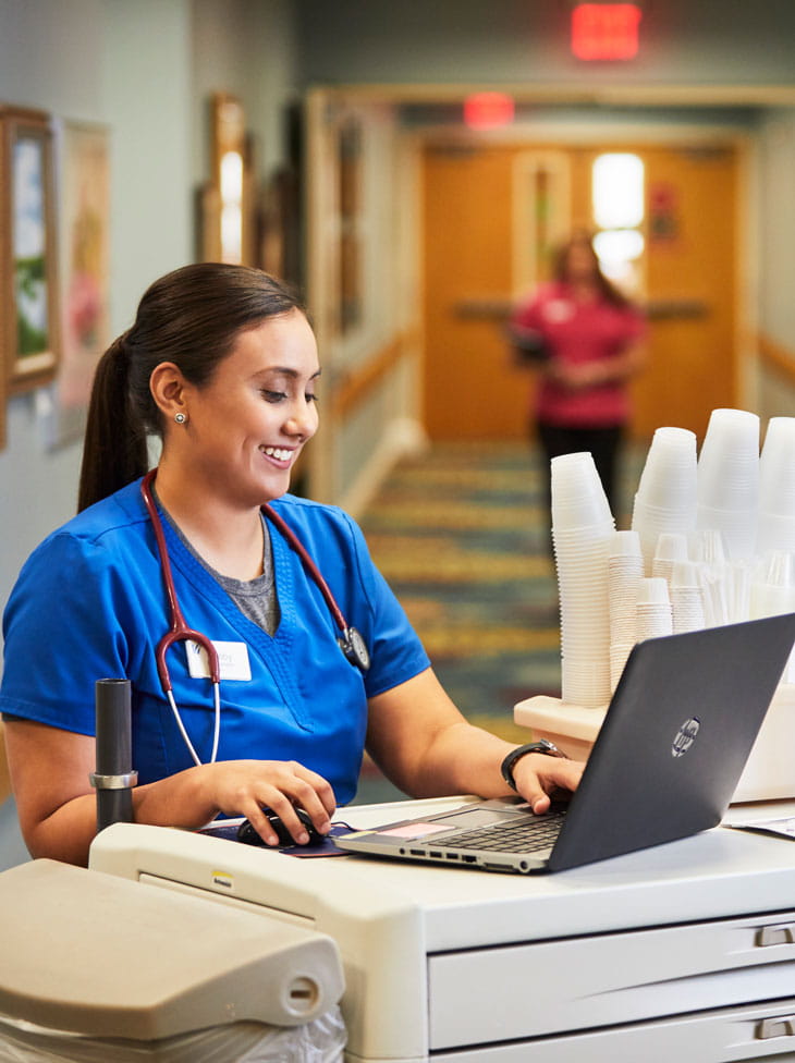 A Vi care professional stands at a nurse's cart.