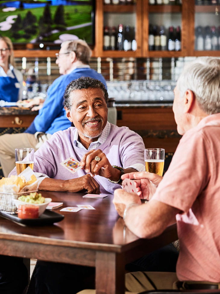 Two men play cards in a bar.