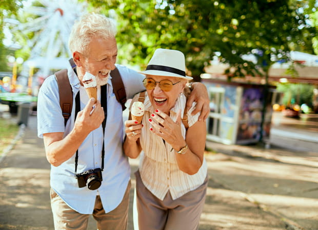 A man and woman laugh while eating gelato.