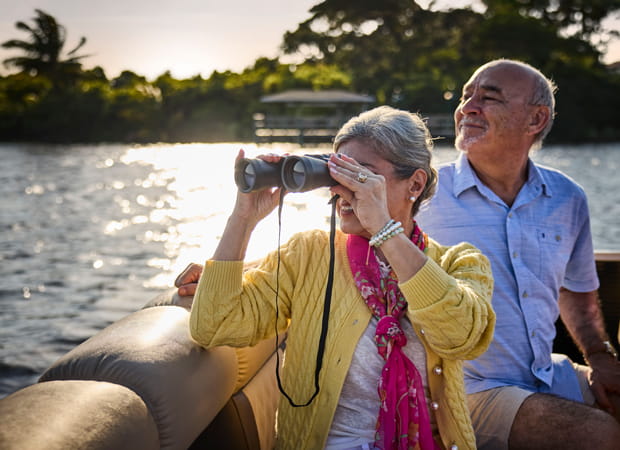 A woman in a cardigan and scarf looks through binoculars.
