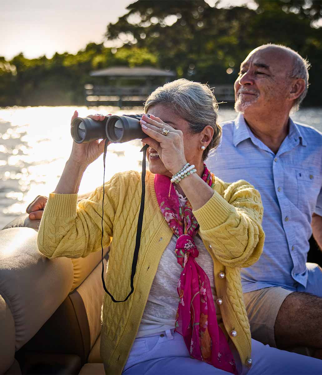 A couple on a boat looking out with binoculars. 