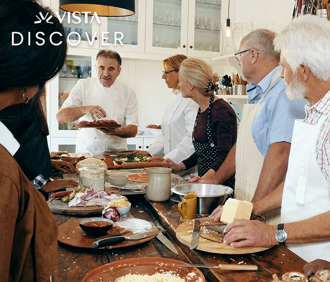 A group of adults watch a chef demo.