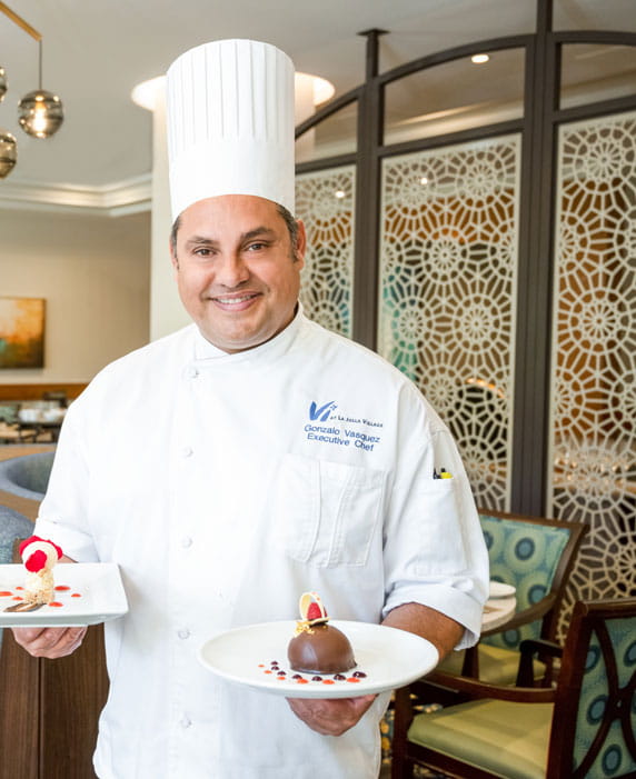 Chef Gonzalo holds two plates of food